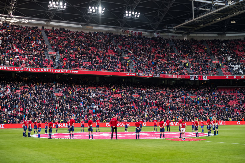Teams on the pitch before an international match in a full stadium