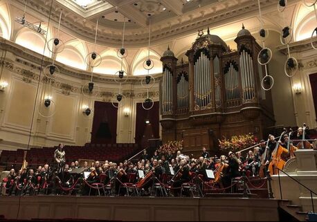 Orchestra in a concert hall with organ during a tour